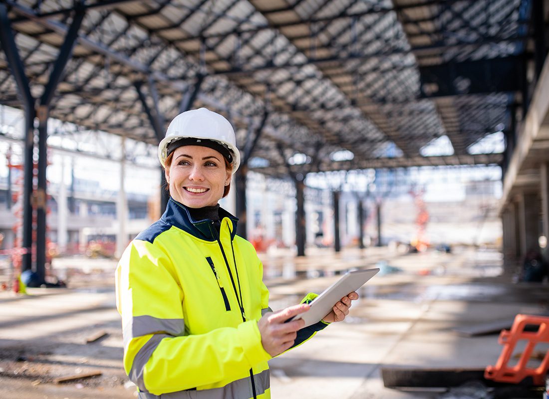 Read Our Reviews - Portrait of a Smiling Female Contractor Holding a Tablet in Her Hands While Standing on a Construction Jobsite